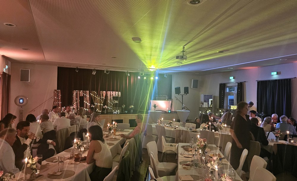 Festlich beleuchteter Empfangssaal mit feiernden Gästen und DJ-Setup